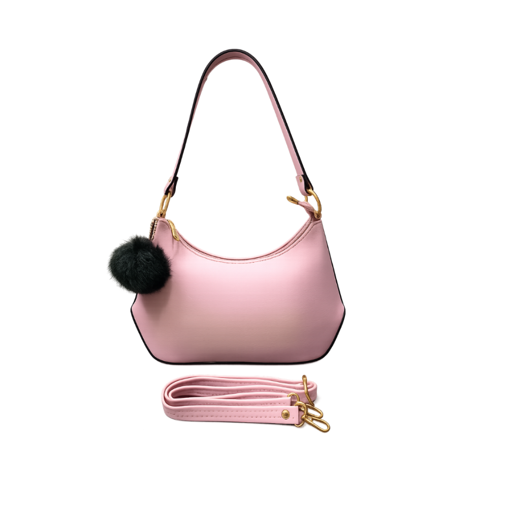 A light pink crescent-shaped shoulder bag with a black pom-pom charm and gold-tone hardware, shown with a detachable pink strap on a plain white background.